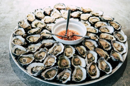 White sauce cup centered on a round plate encircled with three layers of shellfish.